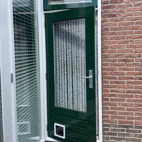 Voordeur in frisse groene lak met kattenluikje