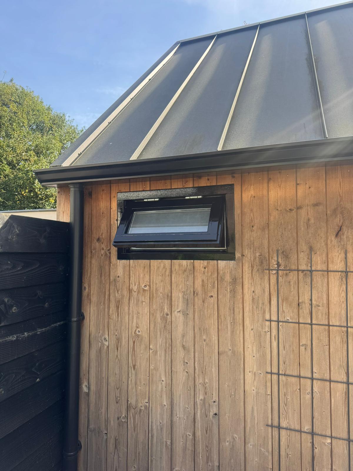 Klepraam met zwarte hoogglans lak in houten gevel