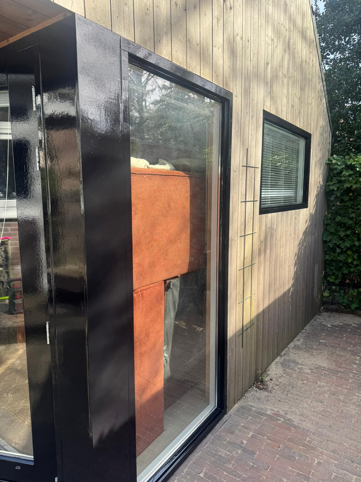 Zwart gelakt kozijn met grote ruit in houten gevel